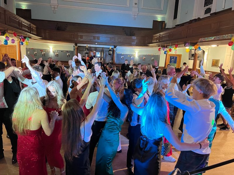 A packed grand-hall dancefloor, hands in the air